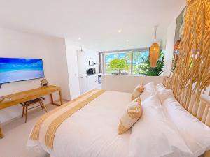 Un dormitorio grande y blanco con una cama grande y un televisor. en Case à Sucre Peaceful retreat with sea view and beach direct access, en Anse Marcel 