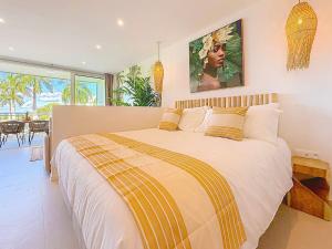 Un dormitorio con una cama grande con almohadas amarillas y blancas. en Case à Sucre Peaceful retreat with sea view and beach direct access, en Anse Marcel 