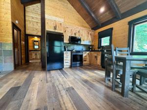a kitchen with a table and a black refrigerator at Mountaineer Creekside Cabin - Private Hot Tub in Golden