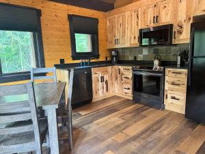 a kitchen with wooden cabinets and a black appliances at Explorer Creekside Cabin - Private Hot Tub in Golden +24 photos
