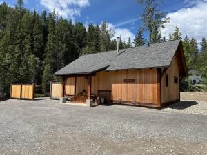 a large wooden barn with trees in the background at Explorer Creekside Cabin - Private Hot Tub in Golden