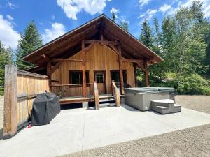 a large wooden building with a patio and a grill at Mountaineer Creekside Cabin - Private Hot Tub in Golden