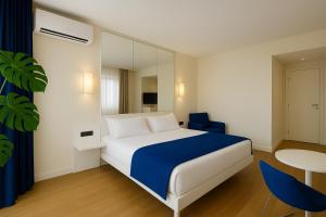 una camera da letto con un letto bianco e una sedia blu di Elite Class Sea View Aparthotel In Orbi City Batumi a Batumi