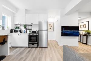 a kitchen with white cabinets and a stainless steel refrigerator at The Sherbrooke Suite in Montreal