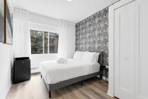 a bedroom with a large white bed and a window at The Sherbrooke Suite in Montreal