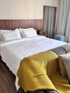 a white bed with a yellow blanket on it at استوديو فندقي in An Nikāshah