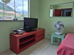 a bedroom with a dresser with a tv and a fan at quarto triplo in Caraguatatuba