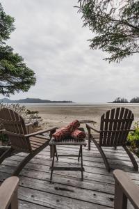 two chairs sitting on a wooden deck with a blanket on it at Chesterman on the Point - Beachfront in Tofino