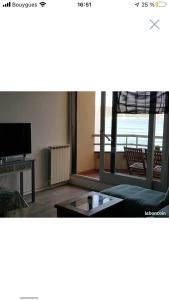 a living room with a tv and a couch and a table at Splendide T2 face à la mer, terrasse, wifi in Hendaye
