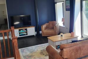 a living room with a couch and a tv and chairs at 3 Bed House - Sea Views Balcony Parking Pets in Innellan