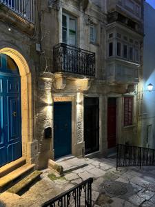 ein Gebäude mit blauen Türen und einer Bank davor in der Unterkunft Phi Home Bormla in Vittoriosa