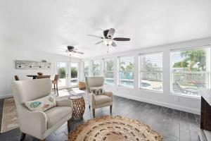 a living room with two chairs and a ceiling fan at Manatee Cove Waterfront Home w Dock Pool in Cocoa Beach