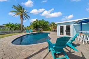 a swimming pool with blue chairs and a palm tree at Manatee Cove Waterfront Home w Dock Pool in Cocoa Beach