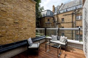 a balcony with two chairs and a brick wall at Buckingham & Lloyds in London