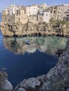 a small boat in a body of water in front of buildings at Soffio Marino in Polignano a Mare