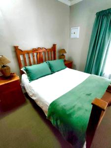 a bedroom with a large white bed with green sheets at De Valk & Tak Manor in Bloemfontein