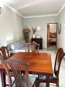 a living room with a wooden table and chairs at De Valk & Tak Manor in Bloemfontein