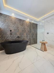 White Cottage Boutique Guesthouse في سواكوبموند: حمام مع حوض استحمام أسود وجدران من الرخام +37 صورة