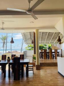 ein Esszimmer mit Tischen und Stühlen sowie einem Deckenventilator in der Unterkunft Hotel Emanuel Kabalana in Piyadigama