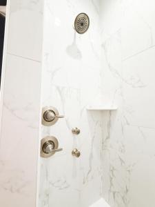 a shower with white marble walls and chrome fixtures at THAT House - NEW Oceanview Steps to the Beach in Kill Devil Hills +44 photos