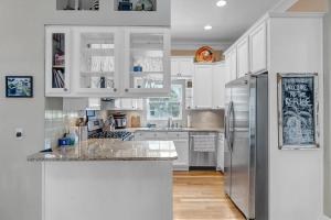 una cucina con mobili bianchi e un frigorifero in acciaio inossidabile di Aqua Vista - Cozy beach home w BBQ & large deck a St. Augustine