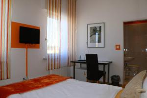 a hotel room with a bed and a desk and a television at Casa Hotel Neu-Isenburg in Neu Isenburg