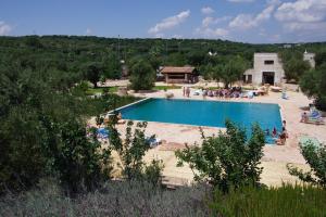 a large swimming pool with people sitting around it at Masseria Sciaiani Piccola in Villa Castelli