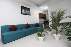 a blue couch in a living room with potted plants at Capital O Levanti Near Aravali Biodiversity Park in Gurgaon