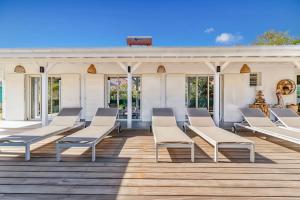 a porch with white chairs on a wooden deck at Villa Bohème in Terre-de-Haut