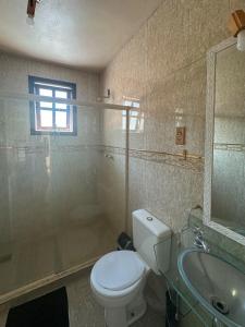 a bathroom with a toilet and a sink and a mirror at Buena Onda Suites in Abraão