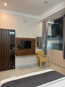 蒂鲁瓦纳马莱Indhu Residency的卧室设有壁挂式电视和椅子