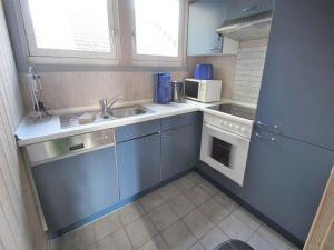 a small kitchen with blue cabinets and a sink at exklusives skandinavisches Ferienhaus in Granzow +15 photos