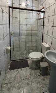 a bathroom with a shower and a toilet and a sink at Pousada Samburá in Garopaba
