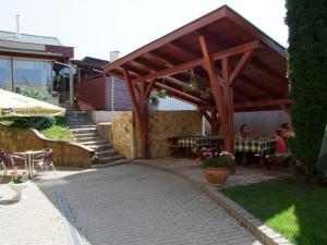 a patio with a wooden pavilion with people sitting at tables at Lugas Hotel in Nyíregyháza