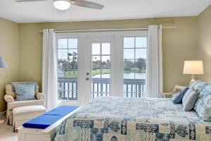 a bedroom with a bed and a balcony at Beachy Vibes - 2BR w lake views & screened sunroom in Ponte Vedra Beach