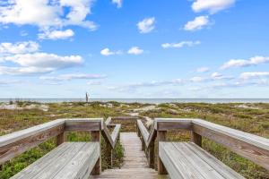 a wooden boardwalk to the beach under a blue sky at Oceanview Escape Private Beach Access in South Cocoa Beach