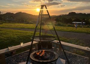 a fire pit with a grill with the sunset in the background at Spacious Valley Views Near City & Coast in Whangarei