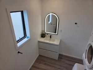 a white bathroom with a sink and a mirror at Spacious Valley Views Near City & Coast in Whangarei