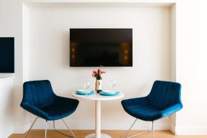 un tavolo con due sedie blu e una TV di Elite Class Sea View Aparthotel In Orbi City Batumi a Batumi