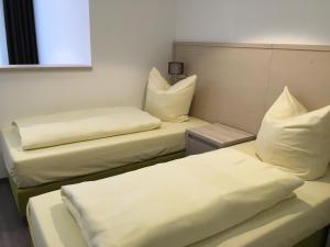 two beds in a room with white sheets and pillows at Hotel Fürsteneck in Bernburg