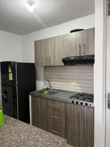 a kitchen with wooden cabinets and a black refrigerator at Apartamento amoblado en parque heredia in Cartagena de Indias