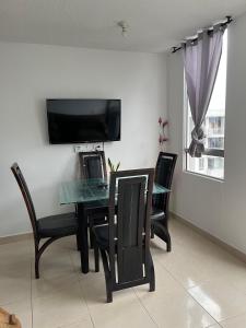 a dining room table with chairs and a television on a wall at Apartamento amoblado en parque heredia in Cartagena de Indias