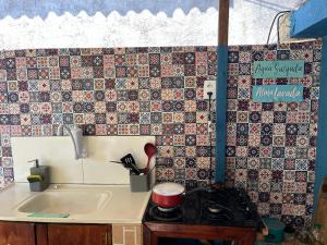 a kitchen with a sink and a tile wall at Buena Onda Suites in Abraão