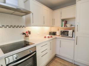 a white kitchen with white cabinets and a microwave at Keepers Cottage in Warminster +30 photos