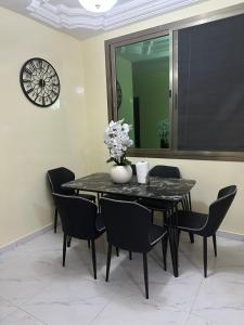 Una mesa de comedor con sillas negras y un reloj. en Express at home, en Dakar