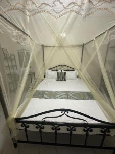 ein Schlafzimmer mit einem Himmelbett mit weißen Vorhängen in der Unterkunft Express at home in Dakar