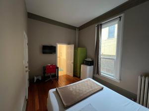 a small bedroom with a bed and a window at Klaus Guesthouse in Toronto