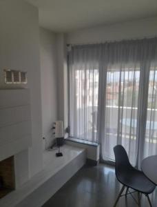 a living room with a table and chairs and a window at Anesis Premium Living Ιωάννινα in Ioannina