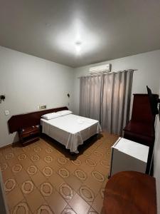 ein Schlafzimmer mit einem weißen Bett und einem Klavier in der Unterkunft Novo Mundo Hotel in Barra do Garças