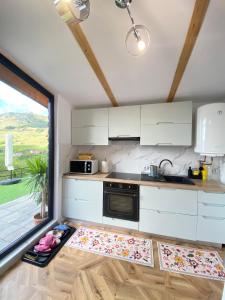 una cucina con mobili bianchi e una grande finestra di Catunu lupului village Cabana Monte Benito a Cotorăşti